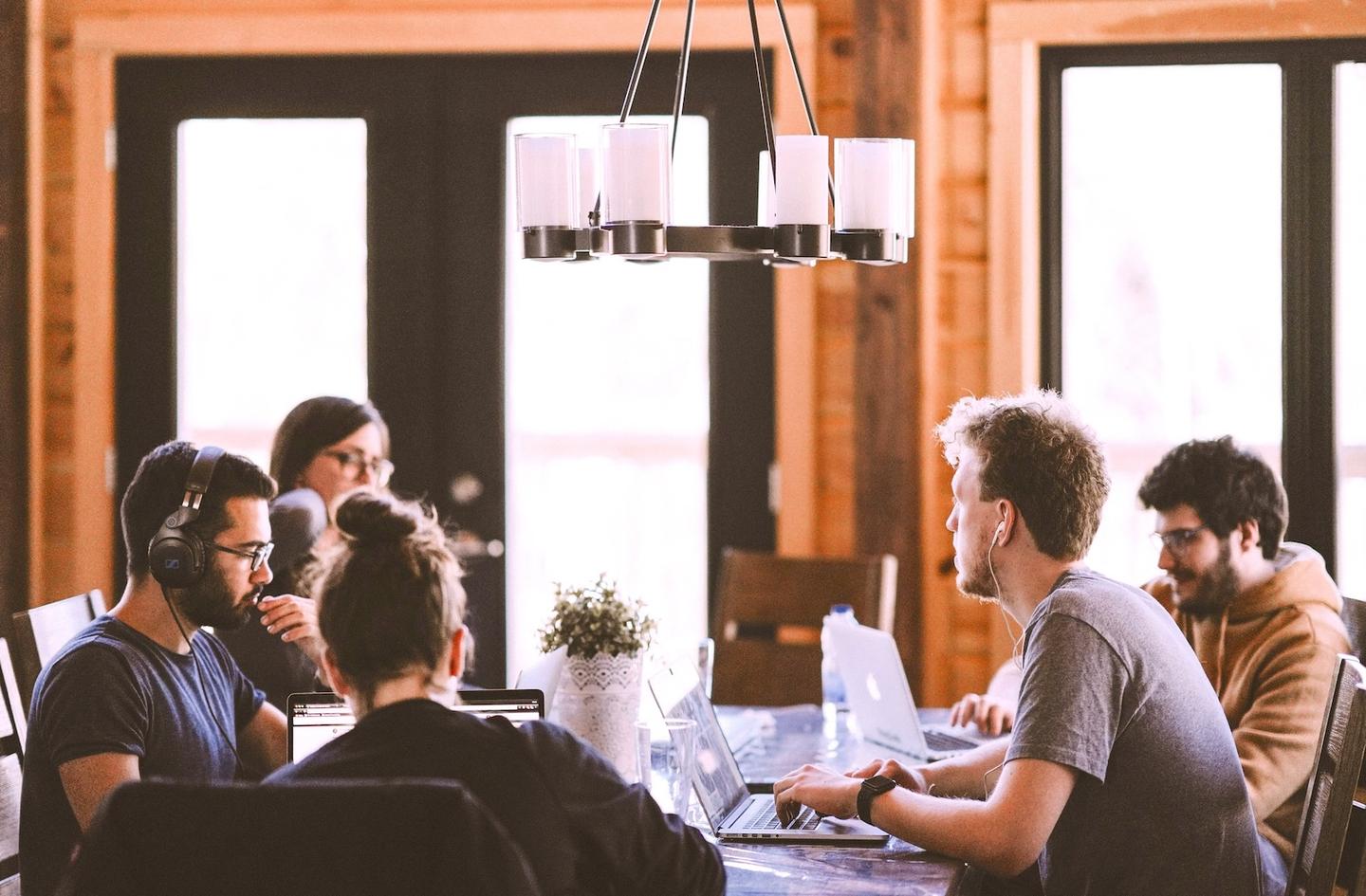 A group of people working at an office table in an open plan office